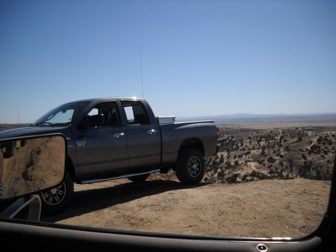 1986 Ford Bronco II - A gray pickup truck is parked on a dirt hill with a vast desert landscape in the background under a clear blue sky.