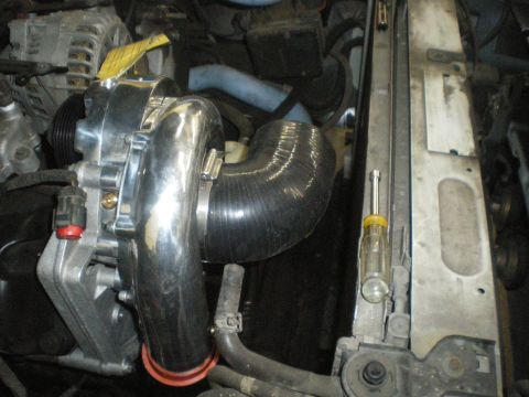 1998 Ford Crown Victoria - Close-up of a supercharger and intake piping during installation.