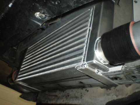 1998 Ford Crown Victoria - angled underside view of an aluminum bar-and-plate intercooler joined to a black silicone boot on its end tank.