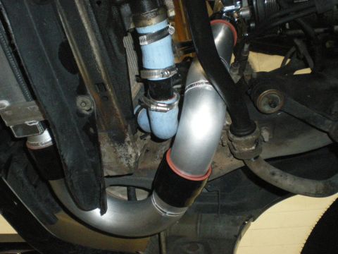 1998 Ford Crown Victoria - underside view showing blue silicone hoses with clamps and a polished aluminum pipe routed near suspension components.