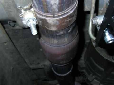 1990 Ford Bronco - Close-up view of a vehicle's exhaust system, focusing on the catalytic converter and pipework.