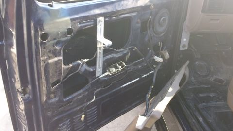 1994 Ford Bronco - The interior of a car door is shown with the door panel removed, revealing the window mechanism and wiring.