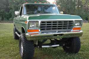 1995 Ford Bronco - Front view of a lifted green pickup truck with prominent chrome grille and large tires.