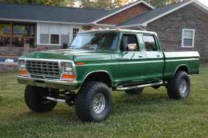 1995 Ford Bronco - This lifted green crew cab pickup truck features a prominent grille, suggesting a 1970s model year.