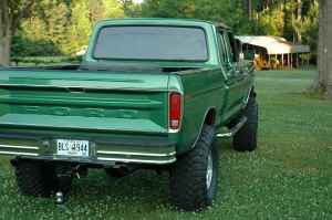 1995 Ford Bronco - This green Ford pickup truck is seen from the rear, lifted with large tires and a visible license plate.
