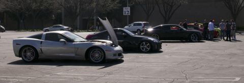 2006 Cadillac STS - Several cars are parked in a lot, with a few people gathered around them.
