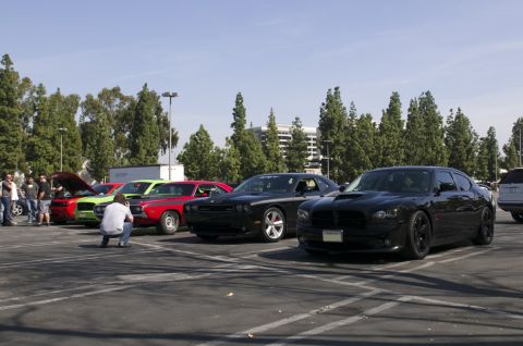 2006 Cadillac STS - A black Dodge Charger is parked in a lot alongside other vehicles, with a photographer crouching to take a picture.