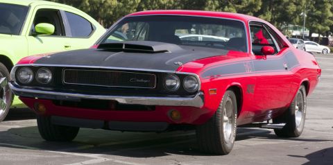 2006 Cadillac STS - Red 1970 Dodge Challenger with black hood scoop and racing stripes parked next to a green car.