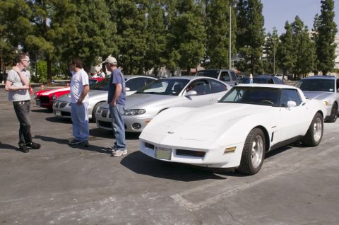2006 Cadillac STS - Several cars and people are gathered in a parking lot on a sunny day.