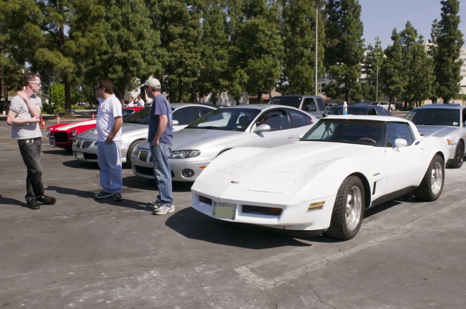 White C3 Corvette parked in a lot with people and other cars