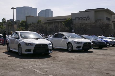 2006 Cadillac STS - Two white Mitsubishi Lancer Evolution cars are parked in a lot outside a shopping mall.