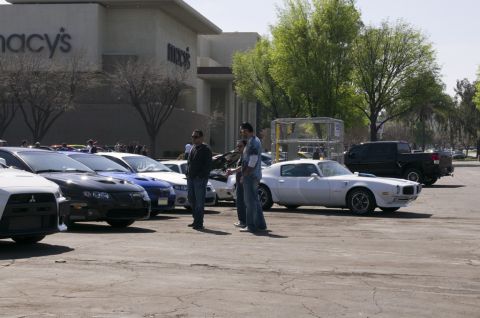 2006 Cadillac STS - A group of cars are gathered in a parking lot outside a Macy's store on a sunny day.