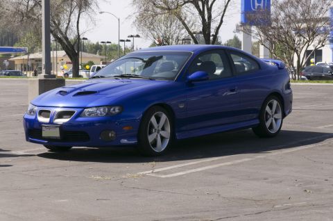 2006 Cadillac STS - A blue coupe with distinctive hood scoops is parked in a lot.