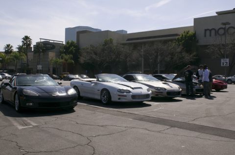 2006 Cadillac STS - Multiple sports cars are parked in a lot outside a shopping center.