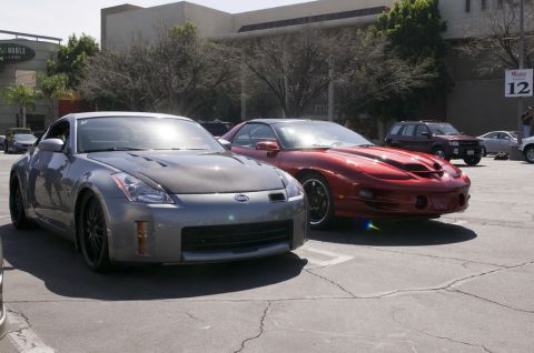 2006 Cadillac STS - Two sports cars, a Nissan 350Z and a Pontiac Firebird, are parked in a lot with a building in the background.