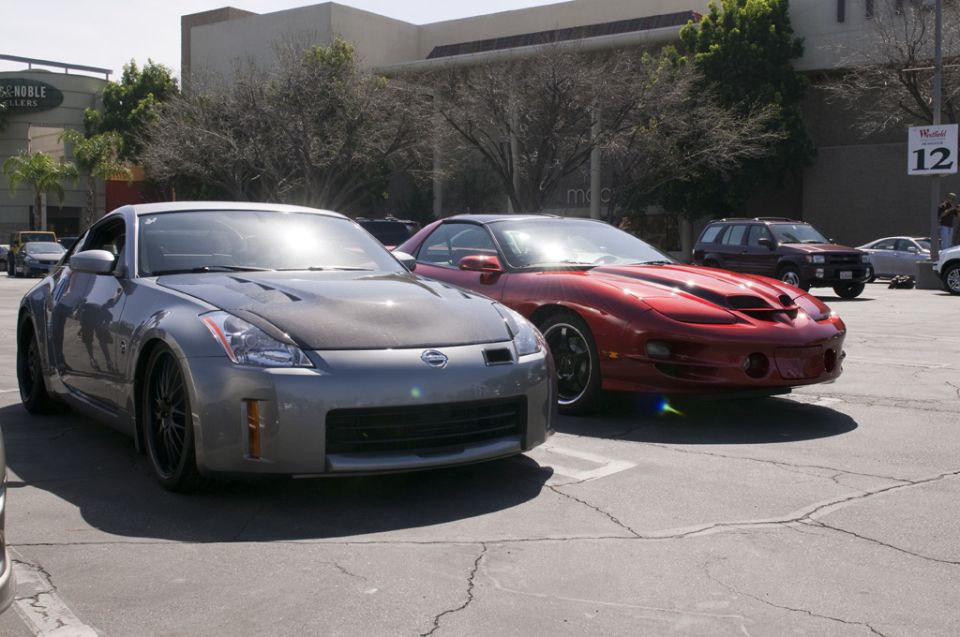 Gray Nissan 350Z with carbon fiber hood parked next to a red Pontiac Firebird