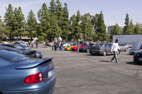 2006 Cadillac STS - A blue sedan with a spoiler is parked in a lot with other cars and people.