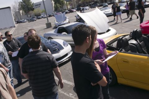 2006 Cadillac STS - People inspect vehicles in a parking lot, with a Macy's store visible in the background.