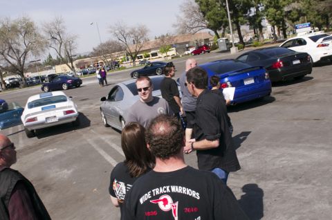 2006 Cadillac STS - A gathering of car enthusiasts in a parking lot with multiple vehicles on display.
