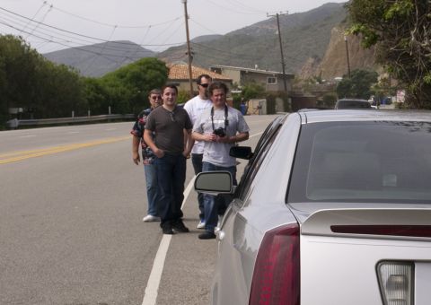 2006 Cadillac STS - Rear view of a silver 2006 Cadillac STS sedan parked on the side of a road with people standing nearby.