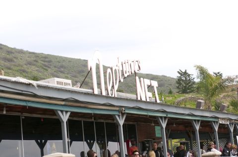 2006 Cadillac STS - A building with a large white sign is visible under a cloudy sky, with green hills in the background.