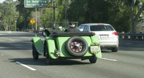 2006 Cadillac STS - A green vintage convertible is seen on the road, a spare tire mounted on the rear and a California license plate.