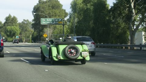 2006 Cadillac STS - Green vintage convertible on highway with a silver car following. License plate TAG 9062.