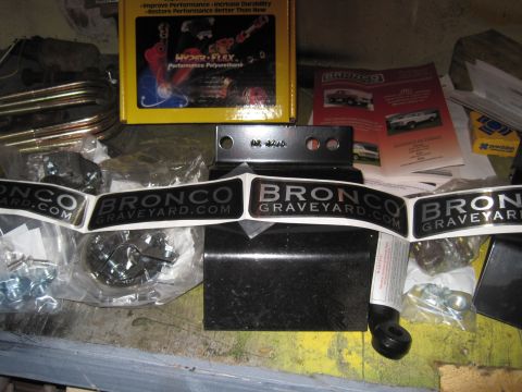 1979 Ford Bronco - Various parts and promotional materials related to Ford Broncos are laid out on a workbench.