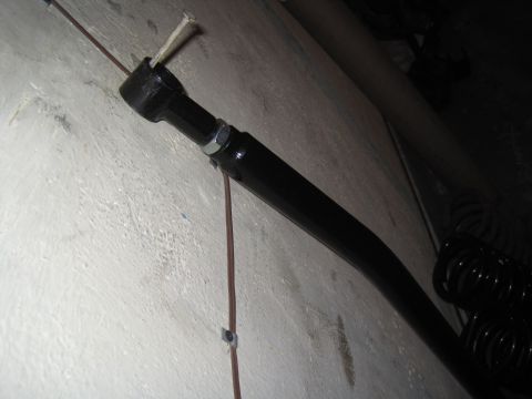 1979 Ford Bronco - Close-up of a black suspension part, likely from a vehicle, against a textured wall.