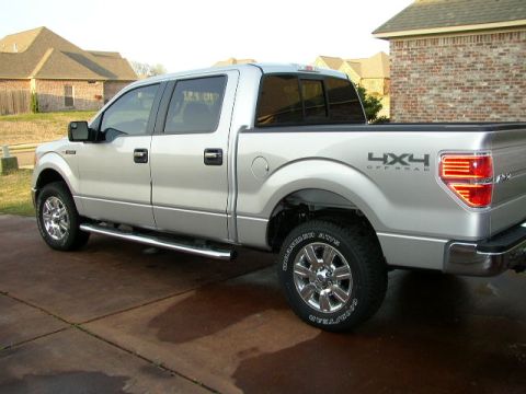 1995 Ford Bronco - Silver pickup truck with chrome side steps and 4x4 Offroad decal on the rear fender.