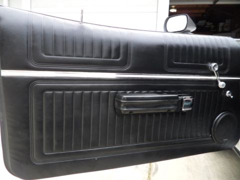 1973 Ford Ranchero - Close-up of a vintage car's black vinyl door panel, showing ribbed texture and chrome accents.