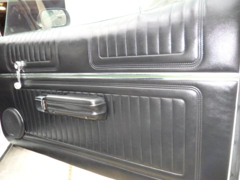 1973 Ford Ranchero - Interior view of a 1973 Ford Ranchero's black door panel, showing its distinctive stitching and chrome accents.