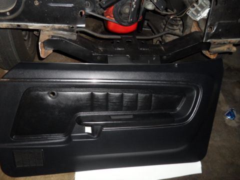1973 Ford Ranchero - A black car door panel is shown with visible engine parts in the background.