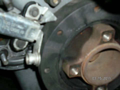 1996 Ford Bronco - A close-up view of an engine timing pointer and a brake rotor assembly.