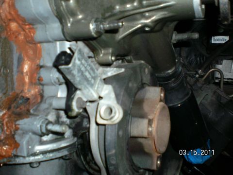 1996 Ford Bronco - Flash close-up down the front of a V8 engine showing the timing pointer tab bolted to the timing cover next to the harmonic balancer with i…