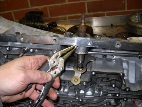1993 Ford C-150 (Centurion Conversions) - A mechanic uses pliers to adjust a part on a vehicle's transmission during a rebuild.
