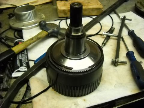 1993 Ford C-150 (Centurion Conversions) - Close-up of a transmission component with various tools scattered around it on a workbench.