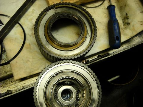 1993 Ford C-150 (Centurion Conversions) - Disassembled transmission clutch packs and gears are laid out on a workbench with a screwdriver.