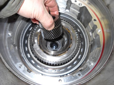 1993 Ford C-150 (Centurion Conversions) - A hand inserts a gear into the internal components of a transmission, likely during a rebuild process.
