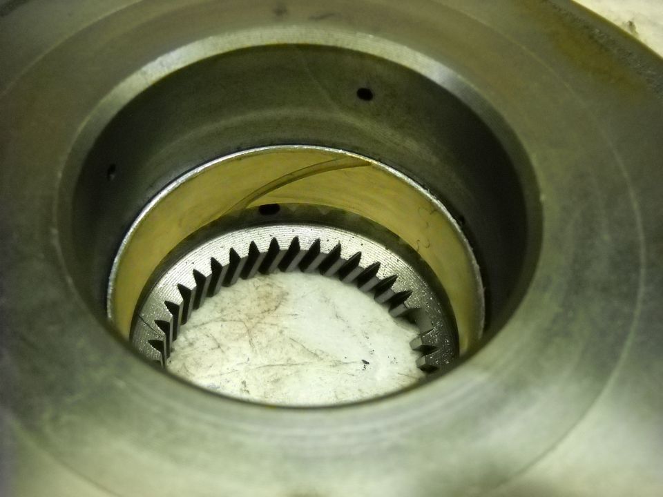 Close-up of a metal gear with teeth inside a cylindrical housing with a yellow band