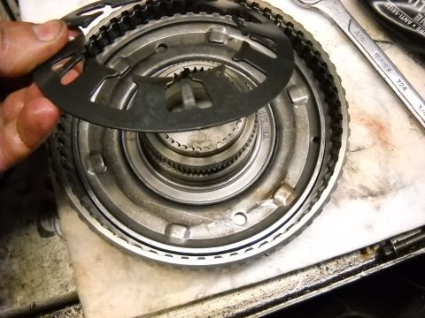 1993 Ford C-150 (Centurion Conversions) - Close-up of a transmission clutch pack being disassembled, with a metal plate held by a hand.