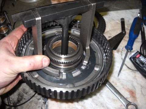 1993 Ford C-150 (Centurion Conversions) - A close-up view shows a transmission planetary gear set being disassembled using a specialized puller tool.