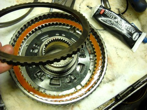 1993 Ford C-150 (Centurion Conversions) - A mechanic is shown assembling an automatic transmission clutch pack, with a tube of engine assembly lube in the background.
