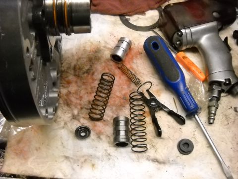 1993 Ford C-150 (Centurion Conversions) - Various transmission components and tools are spread across a workbench, suggesting a repair or rebuild process.