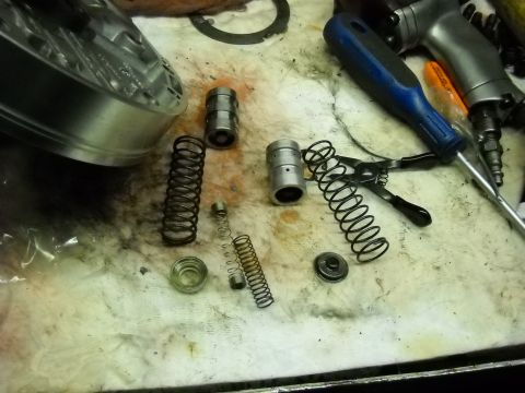1993 Ford C-150 (Centurion Conversions) - Various transmission parts and tools are laid out on a workbench, suggesting a repair or rebuild process.