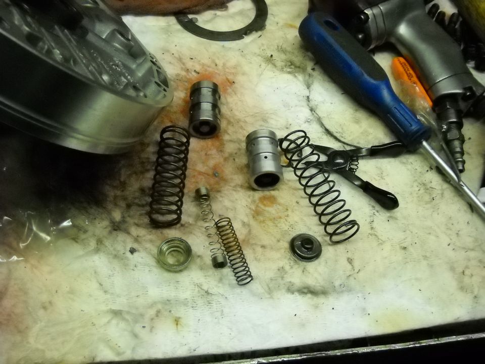 Transmission accumulator pistons and assorted springs laid out on a shop bench