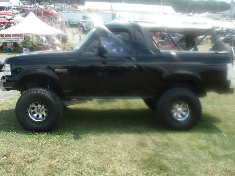 1988 Ford Bronco - Side view of a lifted 1988 Ford Bronco at an outdoor car show.