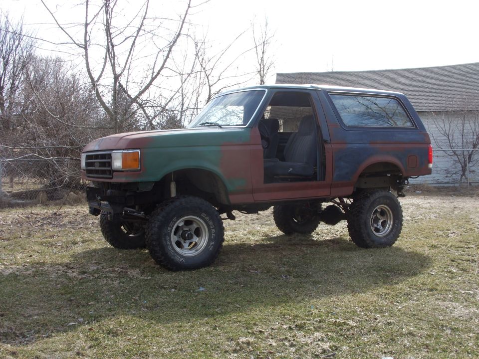 Lifted 1987 Ford Bronco with camouflage paint and open driver's door