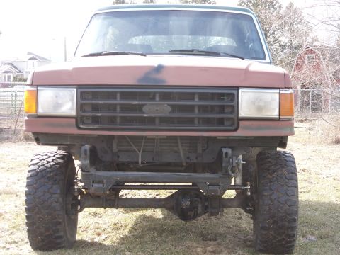 1988 Ford Bronco - The front of a lifted 1987 Ford Bronco shows its grille and large tires.