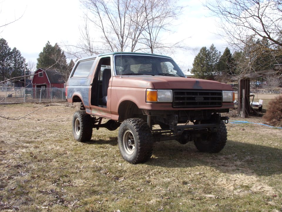 Lifted Ford Bronco with doors removed, primer paint, and aftermarket wheels